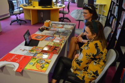 Dwie kobiety przy książkach i tablecie.