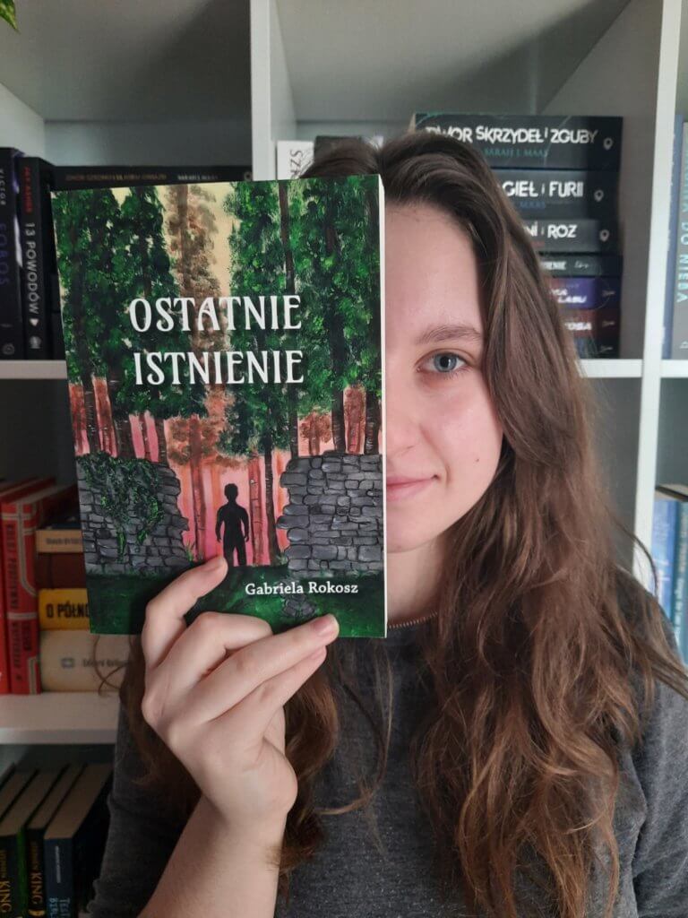 Autorka chowa się za swoją książką pod tytułem Ostatnie Istnienie.