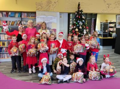 Grupowe zdjęcie dzieci z Mikołajem i prezentami.