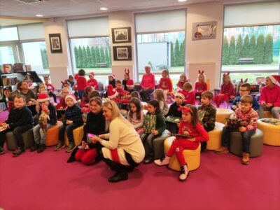 Grupa dzieci siedząca na pufie oczekuję spotkania z mikołajem.