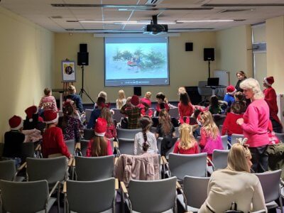 Grupa dzieci na sali konferencyjnej oglądająca projekcje.