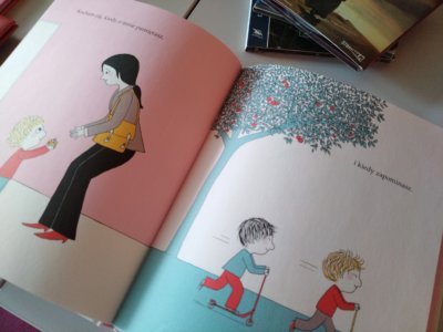 Otwarta książka. Na lewej stronie jest matka z dzieckiem, które daje jej prezent z opiesem Kocham cię kiedy o mnie pamiętasz. Na prawej stronie dwoje dzieci bawią się na hulajnodze z podpisem - I kiedy zapominasz.