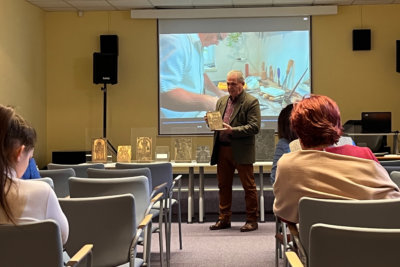 Józef Lewkowicz z drzeworytem, w tle film opowiadający o sztuce drzeworytu.