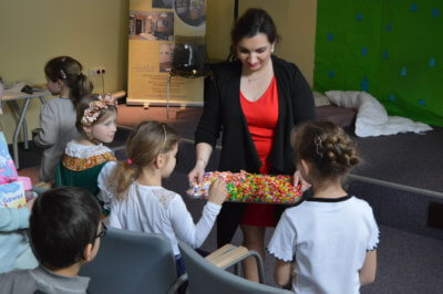 Pani częstuję tacą pełną cukierków dzieci.