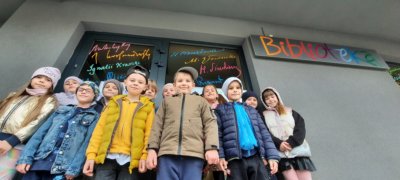 Zdjęcie grupowe dzieci przed biblioteką.
