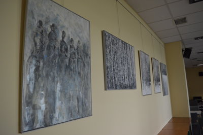 Sala konferencyjna biblioteki z wyeksponowanymi obrazami o podobnej tematyce i kolorystyce.
