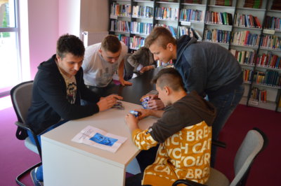 Czterech nastolatków próbuje zrobić piramidę z kart.