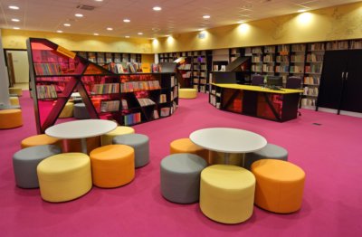 Pufy w czytelni dziecięcej na tle czytelni i książek.