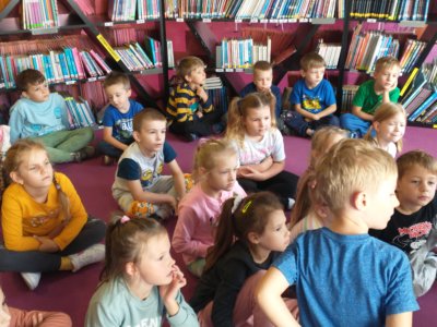 Dzieci siedzące w czytelni dziecięcej.