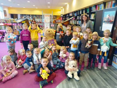 Grupa dzieci trzymająca i tuląca pluszowe misie.