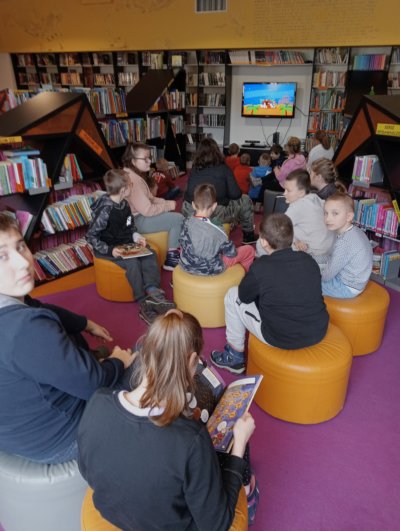 Grupa dzieci siedzących na pufach.