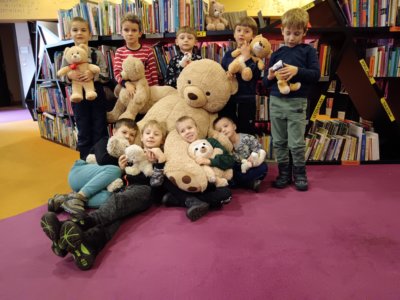 Grupa dzieci przytula dużego pluszowego misia.