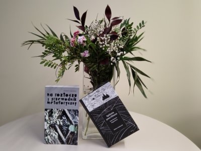 Dwie książki oparte o wazon kwiatów.