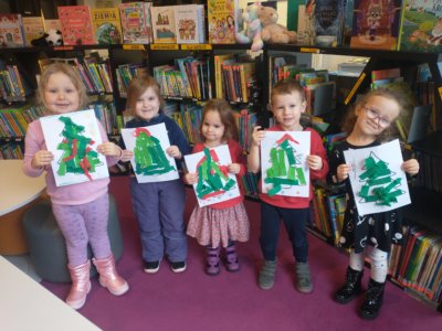 Dzieci trzymające wycinankę przedstawiającą choinkę.