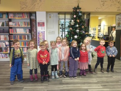 Na zdjęciu uśmiechnięta grupa dzieci przedszkolnych pozuje przy bibliotecznej choince