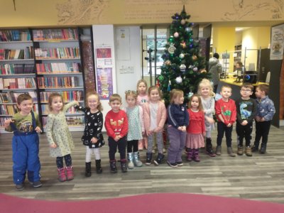 Na zdjęciu uśmiechnięta grupa dzieci przedszkolnych pozuje przy bibliotecznej choince