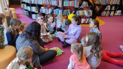 Dzieci siedzące wokół opiekuna i słuchające bajki.