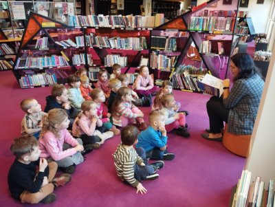 Grupa dzieci siedzących na dywanie i słuchających czytanej bajki.