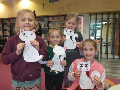 Cztery dziewczynki trzymające wycinane koty.