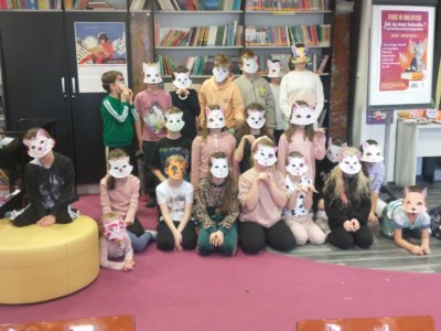 Grupa dzieci w papierowych maskach kota.