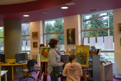 Rodzic z dzieckiem podziwa obraz.